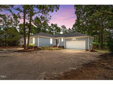 Charming single-story home featuring a two-car garage and a gravel driveway at dusk at 74 Dove Trl Trl, Sanford, NC 27332