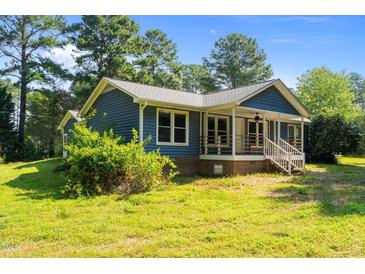 Charming blue home featuring a cozy front porch and well-maintained lawn at 545 Barnette Rd, Louisburg, NC 27549