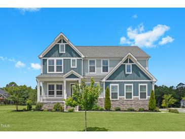 Charming two-story home featuring stone accents, a welcoming porch, and a beautifully landscaped front yard at 300 Ledge Manor Dr, Holly Springs, NC 27540