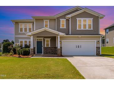 Two-story home featuring a blue front door and an attached two-car garage with verdant lawn at 812 Teal Lake Dr, Holly Springs, NC 27540