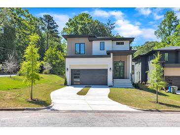 Striking modern home with a two-car garage, sleek gray door, manicured lawn, and a blend of textures on the facade at 2601 Mayview Rd, Raleigh, NC 27607