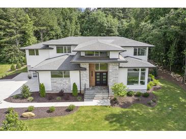 Stunning front exterior with stone accents, a modern double-door entrance, and lush, professionally landscaped yard at 213 Westhampton Dr, Pittsboro, NC 27312