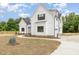 Elegant white farmhouse exterior with a curved driveway, beautiful landscaping, and charming architectural details at 7327 Shawan Rd, Wendell, NC 27591