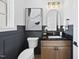 Elegant powder room featuring black granite countertop, arched mirror, and gray paneled accent wall at 5305 Dixon Dr, Raleigh, NC 27609