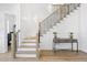 Bright staircase with light wood steps, black iron railing, white wainscoting, and light fixtures at 5305 Dixon Dr, Raleigh, NC 27609