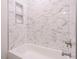 Bright bathtub with marble tiling, built-in niche, and modern shower fixtures at 1521 Havenmont Ct, Raleigh, NC 27608
