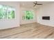 Open living area with modern fireplace, ceiling fan, and large windows showcasing lush greenery at 1521 Havenmont Ct, Raleigh, NC 27608
