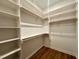 Spacious walk-in closet with wooden floors, built-in shelving, and wooden rods for clothing at 1523 Havenmont Ct, Raleigh, NC 27608
