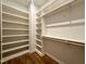Spacious walk-in closet with wooden floors, built-in shelving, and wooden rods for clothing at 1523 Havenmont Ct, Raleigh, NC 27608