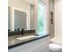 Modern bathroom featuring sleek gray tiling, a large mirror, and a stylish vanity with a contrasting countertop at 1525 Havenmont Ct, Raleigh, NC 27608