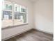 Well-lit bedroom with view of modern home exterior through a large window and wood-look floors at 1527 Havenmont Ct, Raleigh, NC 27608