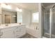 Bathroom featuring a double vanity, large mirror, bathtub, and glass-enclosed shower at 138 New Twin Branch Ct, Smithfield, NC 27577
