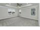 Bright, carpeted bedroom featuring tray ceiling, ceiling fan, and three windows at 138 New Twin Branch Ct, Smithfield, NC 27577