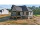 View of the covered back porch with black railing and stairs, black window frames, and gray siding at 4268 Jacks Creek Trl, Burlington, NC 27215