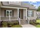 Charming covered front porch with stone-accented stairs and decorative railing at 75 Woodbark Cv # 10, Willow Springs, NC 27592