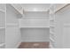 Organized walk-in closet with white shelves and wooden rods at 75 Woodbark Cv # 10, Willow Springs, NC 27592
