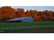 This barn is surrounded by a treeline of colorful fall trees and a large grassy lawn at 804 Ambercrest Place, Durham, NC 27705