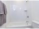 Bright bathroom featuring white tiled shower-tub with modern fixtures and a shelf at 804 Ambercrest Place, Durham, NC 27705