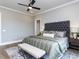 This main bedroom features a gray tufted headboard and decorative pillows and bench on top of a patterned area rug at 804 Ambercrest Place, Durham, NC 27705