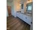 Primary bath with double granite vanity, wood-look floors and closet access at 103 Sage Ln # 009, Four Oaks, NC 27524