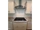 Kitchen stovetop with stainless hood, stone counter tops, and white cabinets at 103 Sage Ln # 009, Four Oaks, NC 27524