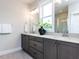 Bathroom featuring dual sinks, gray cabinets, a large mirror, and a view of the walk-in shower at 6059 Scalybark Road, Durham, NC 27712