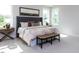 Bright bedroom with a large bed, tufted headboard, bench, and two windows overlooking the backyard at 6059 Scalybark Road, Durham, NC 27712