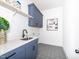 Laundry room features blue cabinets, quartz counters, geometric tile floors, and modern fixtures at 122 W Beech Slope Ct, Chapel Hill, NC 27517