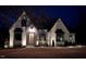 Charming Tudor-style home with landscape lighting, dark trim, and stone accents at night at 43 Laurel Knoll Dr, Pittsboro, NC 27312