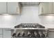Close up of stainless steel stove with six burners, tiled backsplash, and cabinets in modern kitchen at 43 Laurel Knoll Dr, Pittsboro, NC 27312