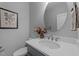 Modern half bath with vanity sink, gray walls, oval mirror, and floral artwork creates a serene atmosphere at 262 Hook Dr # 12, Fuquay Varina, NC 27526