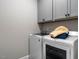 Efficient laundry room featuring a front-load washer and dryer with upper cabinets for storage at 100 Old Garden Ln, Youngsville, NC 27596
