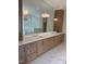 Bright bathroom featuring double sinks, granite countertops, wood cabinets, and a large mirror at 2227 Wheeler Rd, Raleigh, NC 27607