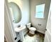 Stylish powder room with pedestal sink, oval mirror, and natural light from the window at 152 Southern Estates Dr, Sanford, NC 27330
