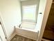 Corner bathtub illuminated by a window, next to a glass shower enclosure at 152 Southern Estates Dr, Sanford, NC 27330