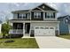 Two-story home featuring light gray siding, a two-car garage, and a welcoming front porch at 152 Southern Estates Dr, Sanford, NC 27330