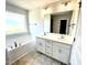 Bright bathroom with double sink vanity, large mirror, soaking tub, and tile flooring at 303 Bishop Ln, Sanford, NC 27330