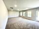 Expansive living room area featuring neutral walls and plush carpeting, with bright windows and door at 303 Bishop Ln, Sanford, NC 27330