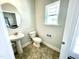Charming powder room features a pedestal sink, toilet, window, and tiled flooring at 303 Bishop Ln, Sanford, NC 27330