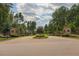Welcoming community entrance with stone pillars, mature trees, circular landscaped median, and inviting roadway at 2633 Trifle Ln, Wake Forest, NC 27587