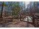 Picturesque wooden bridge over a tranquil stream, surrounded by towering trees and natural woodland beauty at 2633 Trifle Ln, Wake Forest, NC 27587