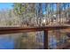 Picturesque pond view framed by a wooden bridge railing with distant neighborhood homes nestled amongst the trees at 2633 Trifle Ln, Wake Forest, NC 27587