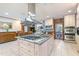 A kitchen island with a granite countertop, stainless steel hood, and built-in gas stovetop, surrounded by custom cabinets at 11 Pine Forest Dr, Siler City, NC 27344