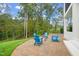 This brick paver patio features four Adirondack chairs and a fire pit, along with a lush green lawn at 1621 Legacy Ridge Ln, Wake Forest, NC 27587