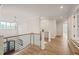 Bright hallway with wood floors, modern railing, decorative light fixture, and an entry door at 1621 Legacy Ridge Ln, Wake Forest, NC 27587