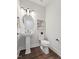 Cozy half bathroom with a pedestal sink, dark hardware, wood flooring and modern decorative art at 1505 Patchings Ln, Knightdale, NC 27545