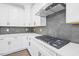 Modern kitchen featuring white cabinets, stainless steel range hood, sleek countertops, and stylish backsplash at 1505 Patchings Ln, Knightdale, NC 27545