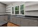 Bright kitchen with large windows, grey cabinets, black countertops, stainless steel appliances and hardwood floors at 3691 Graham Sherron Rd, Wake Forest, NC 27587