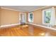 Sunlit living room showcases hardwood floors, tan walls, and white trim, with two windows offering backyard views at 5513 Parkwood Dr, Raleigh, NC 27612