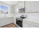 Modern kitchen with gray cabinets, white quartz countertops, and stainless steel appliances at 292 Chestnut Oak Ln, Lillington, NC 27546